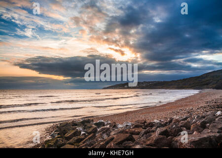 Sunset on Charmouth beach looking towards Lyme Regis. Stock Photo