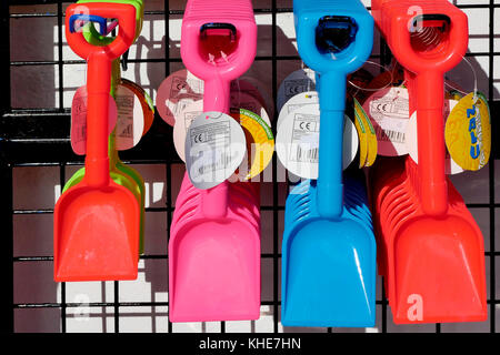 Brightly coloured plastic toy spades on display outside a shop in Lyme Regis in Dorset. Stock Photo