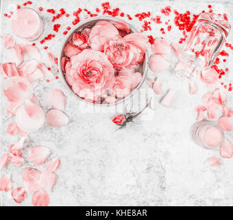 Wellness setting with roses, essential oil, bowl with water and flower petals on light background, top view, border Stock Photo