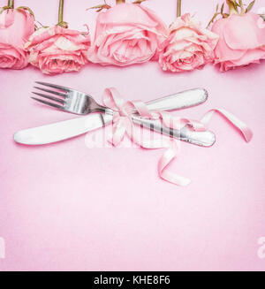 Romantic table place setting with pink roses flowers, cutlery and ribbon. Wedding, invitation , date or greeting card , top view Stock Photo