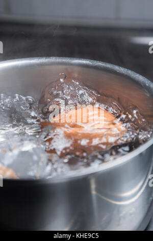 Eggs in boiling water in saucepan on electric hob Stock Photo