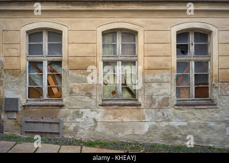 Broken and boarded-up windows in an old abandoned house in Germany Stock Photo