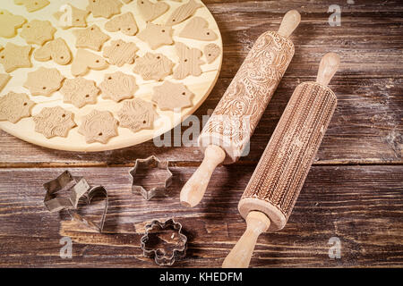 Close-up on a wooden table beautifully lies a lot of toys for a Christmas tree made of brown clay, made in the hand in the form of hearts, stars, bear Stock Photo