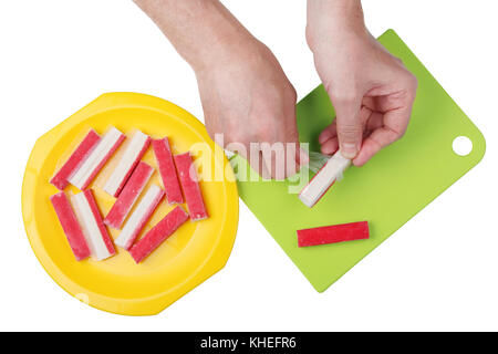 The chef hands cleans the frozen crab sticks from parchment. Isolated on white top view stodio shot Stock Photo