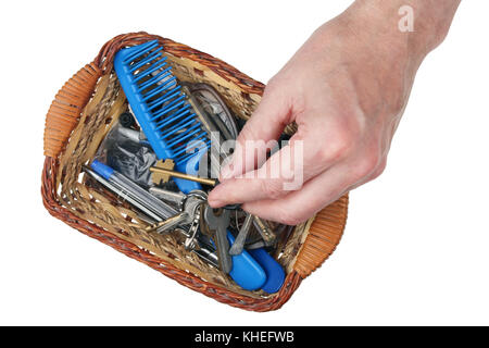 An elderly man takes the keys to the house from a basket with small household things. Stock Photo