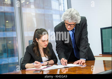 Mature businessman helping a young employee Stock Photo