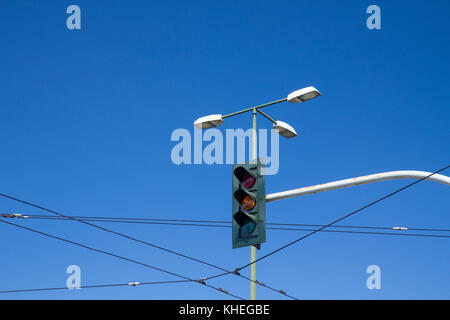 A traffic light, with orange light on, against the blue sky Stock Photo