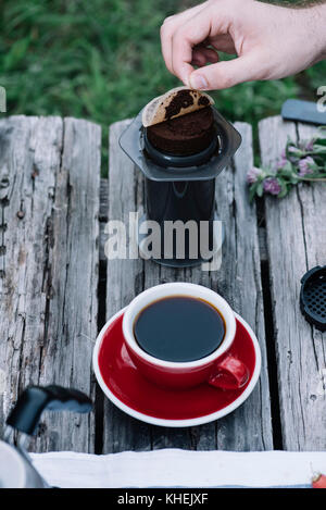 Fresh coffee puck, left from making filter coffee outdoors on the wooden table background Stock Photo