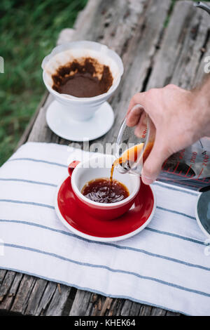 Delicious freshly brewed outdoor pour over coffee pouring into porcelain red coffee cup Stock Photo