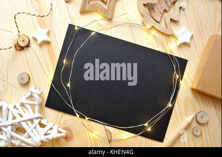 Christmas background black sheet of paper with place for your text and white christmas star and garland on a wooden background. Flat lay, top view photo mockup Stock Photo