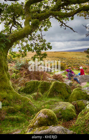 Women sitting enjoying the views by Wistman's Wood, Dartmoor National Park, Devon, UK in September - hdr effect Stock Photo