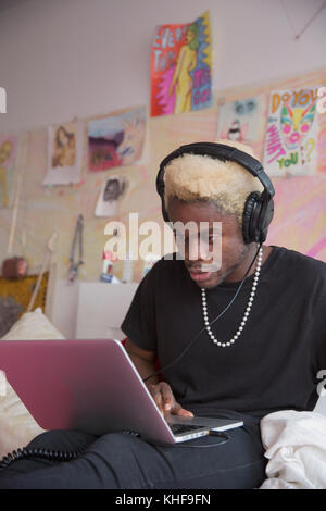 Young man wearing headphones working on his laptop at home Stock Photo