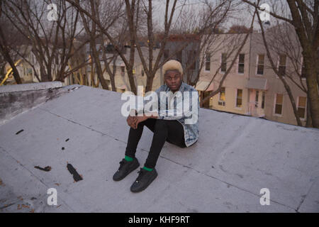 Young man sits on a rooftop Stock Photo