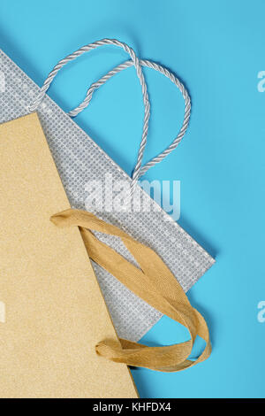 Golden and silver gift bags on blue background. Flat lay Stock Photo