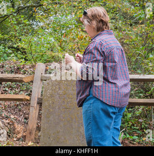 Woman using dowsing rods in rural US Appalachian graveyard Stock Photo