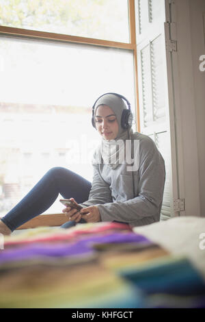 Muslim woman wearing a hijab listening to music Stock Photo
