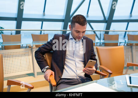 Businessman sitting and uses smartphone in office. Stock Photo