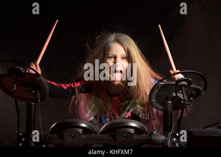 Little caucasian girl drummer with multicolored hair playing the electronic drum kit Stock Photo