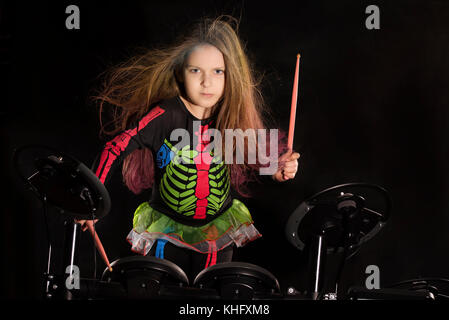 Little caucasian girl drummer with multicolored hair playing the electronic drum kit Stock Photo