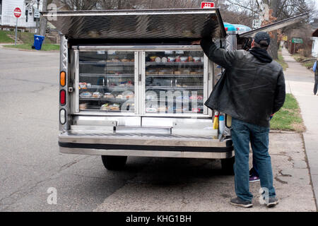 Man raising cover to a mobile lunch truck stuffed full of sandwiches and other goodies in front of a business. St Paul Minnesota MN USA Stock Photo