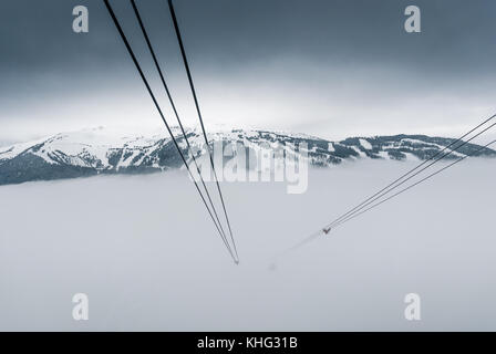 Cable car running between two snow covered mountains at a ski resort Stock Photo