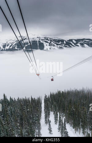 Cable car running between two snow covered mountains at a ski resort Stock Photo