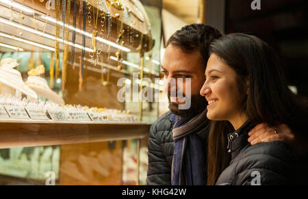 Happy beautiful young couple choosing a wedding rings while smiling while doing shopping in Florence. Stock Photo