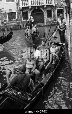 Gondolier on a gondola with tourist and holiday makers waiting in a trafffic jam Stock Photo
