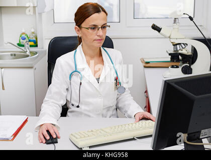 Doctor Working on a Computer at Her Desk Stock Photo