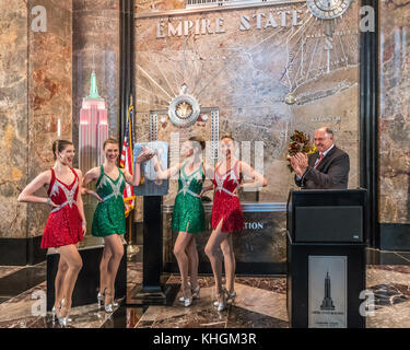 New York, USA. 16th Nov, 2017. Radio City Music Hall Rocketttes turn on the lights of the Empire State Building in red and green in celebration of the opening night of their Christmas Spectacular show. Applauding at right is Joseph 'Joe' Bellina, General Manager of the Empire State building, Credit: Enrique Shore/Alamy Live News Stock Photo