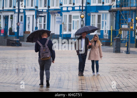 Aberystwyth  Wales UK, Saturday 18 Novemberr 2017  UK Weather: People walking under their umbrellas on the promenade on a grey, overcast, wet and rainy  morning  in Aberystwyth Wales UK      Photo © Keith Morris / Alamy Live News Stock Photo