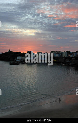Tenby Harbour, South Wales, UK. 19th November, 2017. Cw 5064 Dawn over Tenby Harbour 2 19.11.17   A lone dog walker is greeted by the rising sun as he walks the beach at Tenby harbour in Pembrokeshire South Wales on the morning of Sunday the 19.11.17. Stock Photo