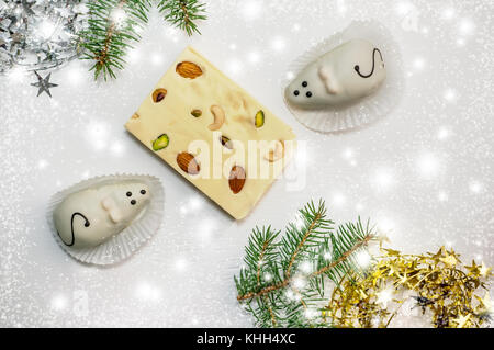 Two cakes in the form of white mice and a marzipan-and-cheese Turkish delight lying on the green branches of a Christmas tree. Copy the place. Close-u Stock Photo