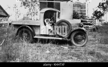 This 1920s photograph features Betty Harwood sitting at the steering wheel of a car in Oakview, Queensland. The image captures early automotive culture and the style of the era. Stock Photo