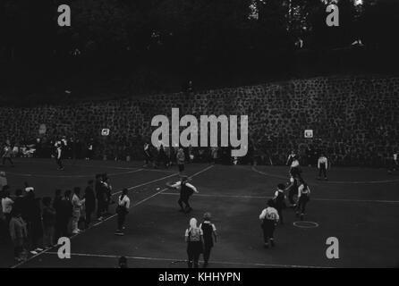 Group of school children playing games on a blacktop playground, other children standing in line and watching, American Samoa, 1960. Stock Photo