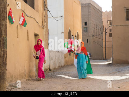 Al Hamra, Oman, November 10th, 2017: Omani girl in national dress with omani flag and baloons in celebration of national day Stock Photo