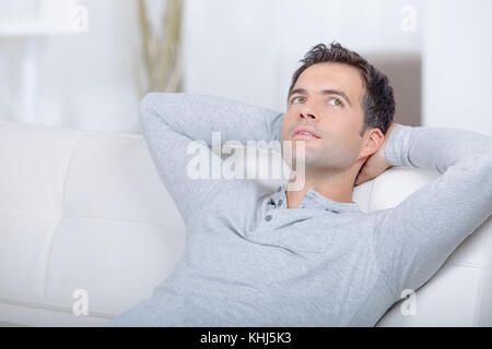 Man deep in thought, sat on sofa Stock Photo