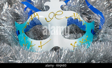 Christmas carnival mask on a silver tinsel background. Christmas masque with christmas tinsel . Close-up Stock Photo