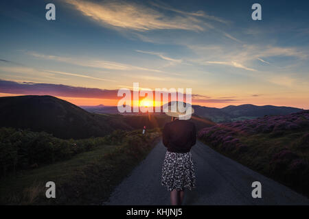 Young Girl on the Top of Mountain Walking Towards Rising Sun Stock Photo