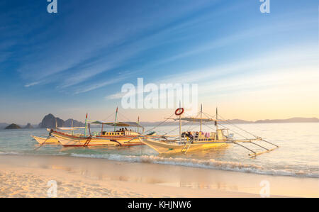 Traditional filipino boats at sunset in Port Barton Stock Photo