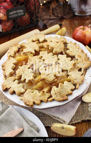 Freshly baked apple pie with top crust cut into autumn leaves shape. Selective focus with shallow depth of field. Stock Photo