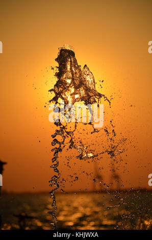 Water splash isolated on sunset colors background. Stock Photo