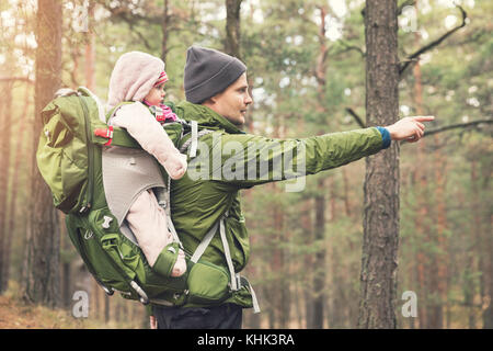 father with baby in child carrier on a hike in the woods Stock Photo