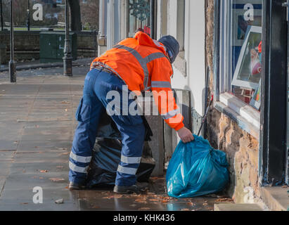 A Durham County Council worker in orange High Visibility coat emptying a street rubbish bin Stock Photo