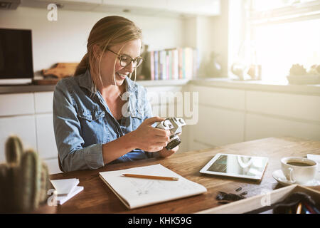 Young female photographer looking at images on her camera while working on her small business at home Stock Photo
