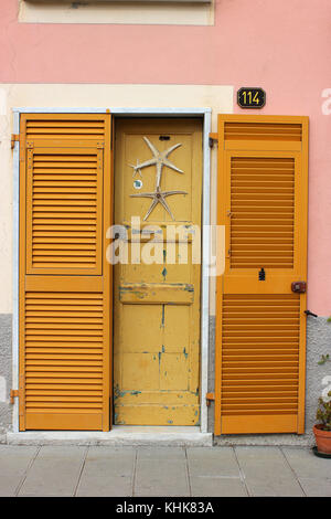 a beautiful seaside yellow door with sea stars and yellow window hatches Stock Photo