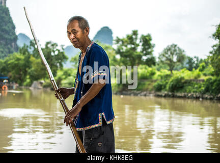 Old Chinese man rowing a boat with a bamboo stick, Li River in Guilin, China Stock Photo