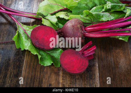 Fresh beetroots with leaves on wooden rustic table.Whole and cut  beetroots Stock Photo