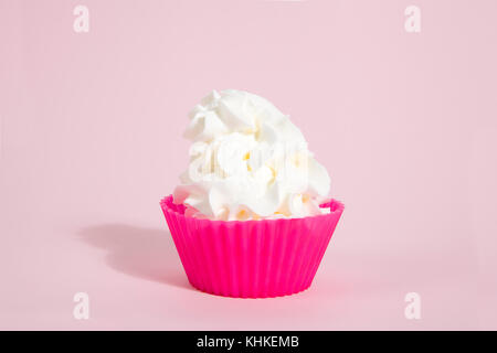 a simple pink silicone cupcake mold filled with whipped cream on a vibrant pink pop background. Gradient colors. Minimal still life photography Stock Photo