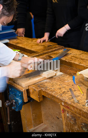 Secondary Education in the UK:  a teacher demonstrating correct saw sawing techniques skill in a woodwork class lesson / design technology Stock Photo